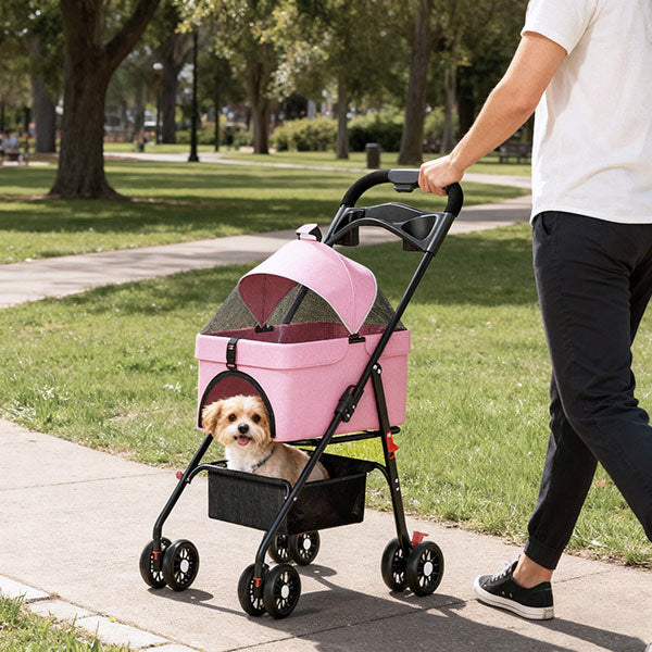 This image shows a person pushing a pink dog stroller in a park.  Inside the stroller, a small dog is visible, comfortably sitting in a compartment.  The stroller has a mesh cover and wheels designed for easy maneuvering.