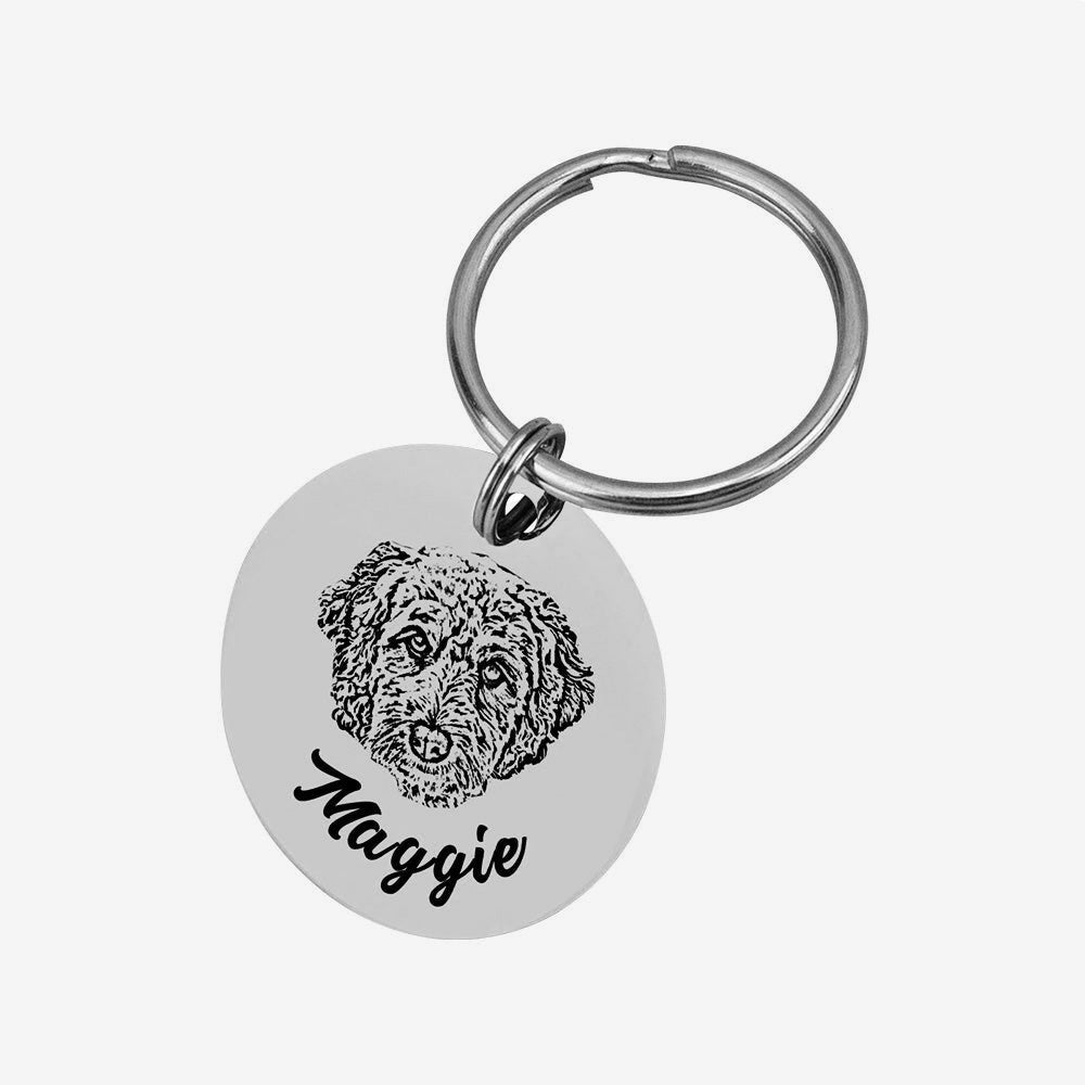 Silver pet keychain with engraved dog portrait and the name “Maggie.”
